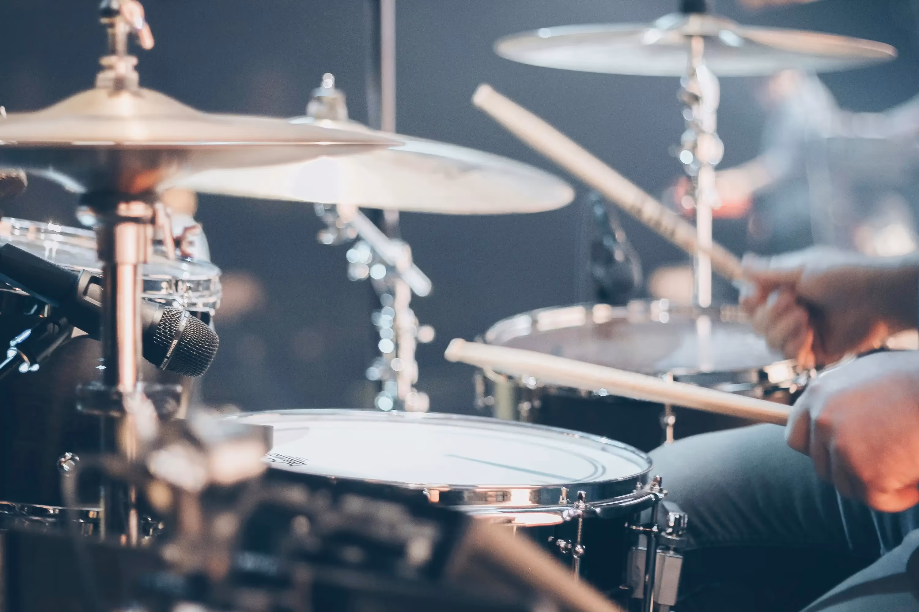 A close-up view of a drum set with a drummer in action, captured during a live performance.